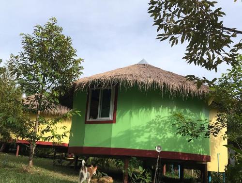 a house with a thatched roof with a dog standing in front at Hippy Hut Koh Chang in Ko Chang