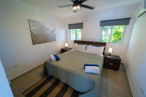 a bedroom with a bed with two night stands and two windows at WOW location Kite Beach Oceanfront Panoramic Views 2 DECKS 2 Bedrooms in Cabarete