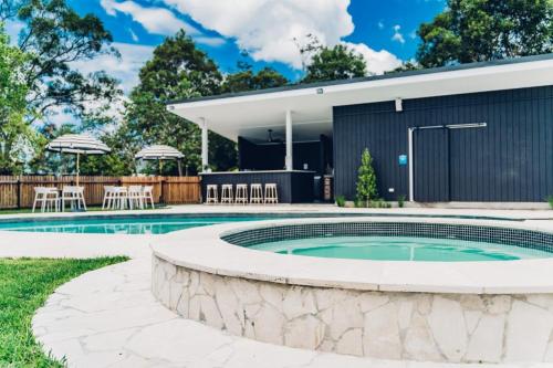 a swimming pool with a patio and a house at The Lodge Bellingen in Bellingen