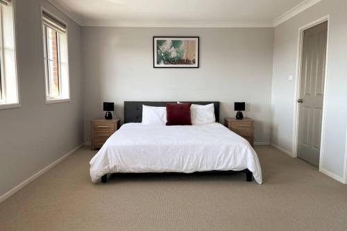 Schlafzimmer mit einem Bett mit weißer Bettwäsche und roten Kissen in der Unterkunft Cheerful 4-bedroom family retreat in Caves Beach in Caves Beach