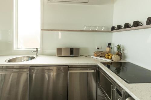 a kitchen with a sink and a counter top at Drift Beach House Getaway in Holloways Beach