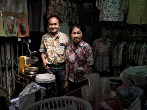 two men are standing in a room with a table at Photohostel in Bangkok