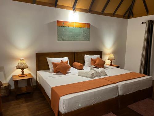 a bedroom with a large bed with two lamps at Saffron Lake Yala in Tissamaharama