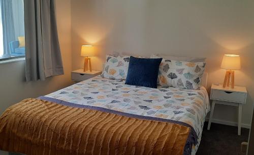 a bedroom with a bed with two lamps on two tables at Cosy on Courtney in Motueka