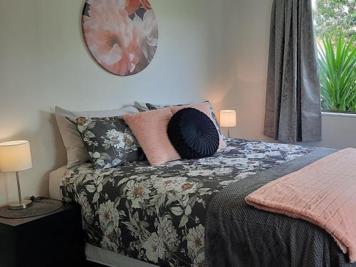 a bedroom with a bed with a floral bedspread and a window at Cosy on Courtney in Motueka