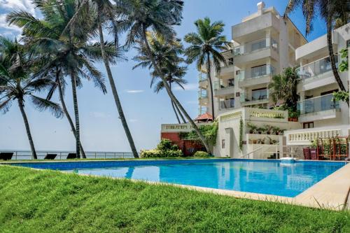 a swimming pool in front of a building with palm trees at Rockholm at the Light House Beach in Kovalam