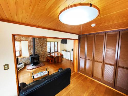 a living room with a black couch and a wooden ceiling at Cottage Hotel Fenice Hakuba 2-Bedroom house - 1km to Hakuba Goryu in Hakuba