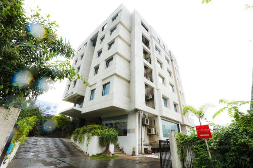 a white building with a red sign in front of it at Hotel Solitaire in Pune