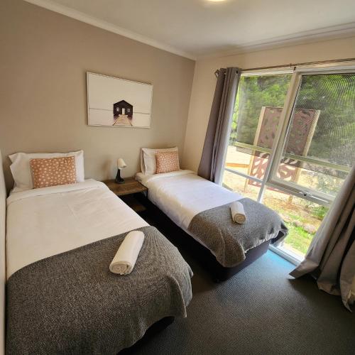 two beds in a room with a window at Bells Beach Cottages in Bellbrae