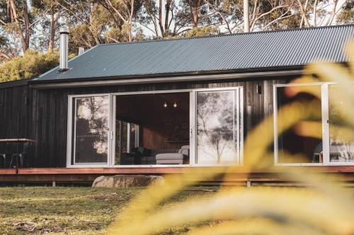 a black house with a large glass door at Seagrass on Sunset Bay in Alonnah