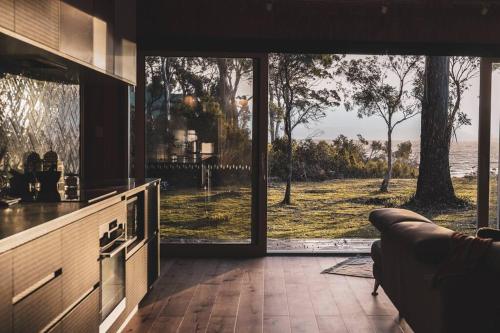 a kitchen with a view of the ocean through a sliding glass door at Seagrass on Sunset Bay in Alonnah