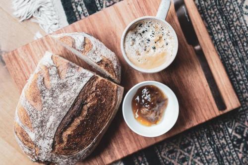 a wooden cutting board with a loaf of bread and a cup of coffee at Seagrass on Sunset Bay in Alonnah