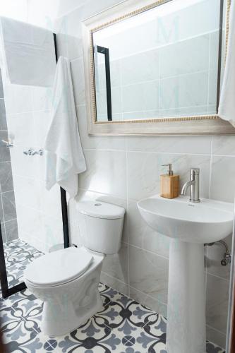 a white bathroom with a toilet and a sink at La Casa de Ana 2 in Jardin