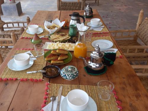 una mesa de madera con comida y bebidas. en Ourika Timalizène le jardin des délices en Tamzerdirt
