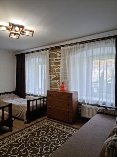 een slaapkamer met een bed, een dressoir en een raam bij Kvartura z dvorukom in Kamjanets-Podilsky