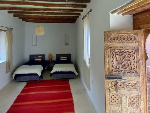Habitación con 2 camas y alfombra roja. en Ourika Timalizène le jardin des délices en Tamzerdirt