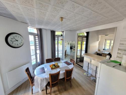 cocina y comedor con mesa y reloj en Bel Appartement Bagneres De Luchon Centre, en Luchon