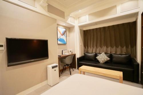 ein Wohnzimmer mit einem Sofa und einem TV in der Unterkunft Hotel 88 Shinsaibashi in Osaka