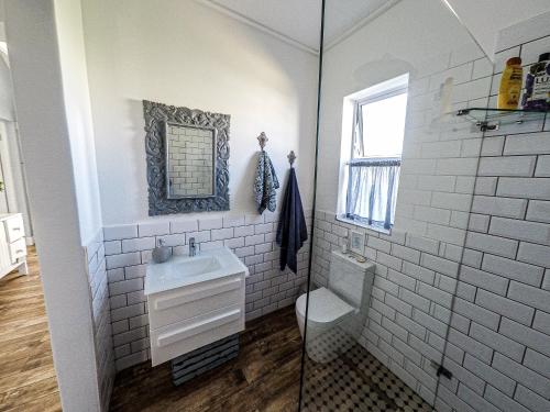 a white bathroom with a sink and a toilet at Kalliste an exclusive retreat in Bettyʼs Bay