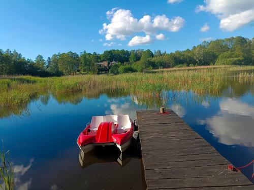 a boat sitting on the water next to a dock at Agroturystyka Alex in Szczecinek