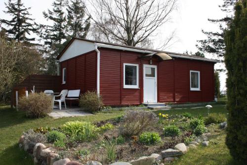 a small red house with a garden in front of it at Ruegen_Fewo 285 in Neu Mukran