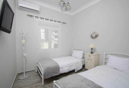 um quarto branco com 2 camas e uma televisão em La Rosa em Ermoupoli