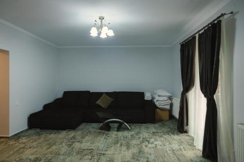 a living room with a black couch and a window at Sub Cetate in Râşnov