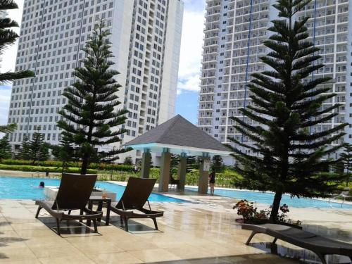 una piscina con sedie e gazebo e alcuni edifici di Heaven Suites, Tagaytay Condominium, Wind Residences a Tagaytay
