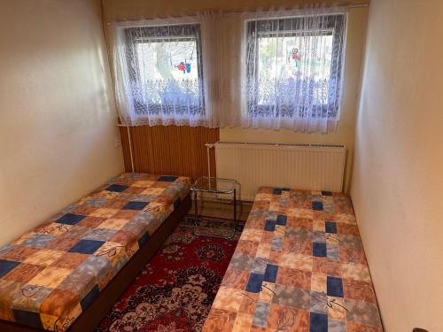 two beds in a room with two windows at Apartmán u vleku in Studénka