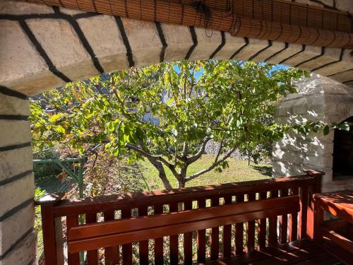 a wooden bench on a porch with a tree at Bed & Wine Djonovic in Virpazar