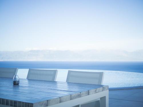 a table and two white chairs and the ocean at WHITE DONKEY BOUTIQUE Hotel in Chrani