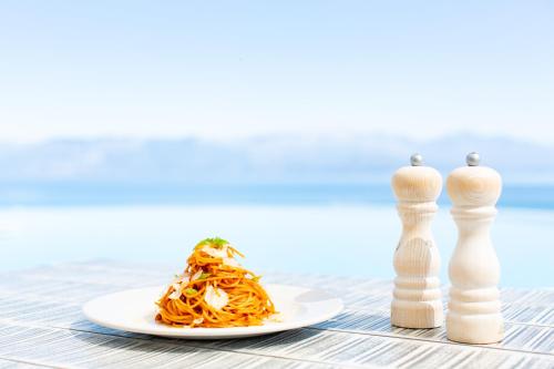 a plate of spaghetti next to a chess piece at WHITE DONKEY BOUTIQUE Hotel in Chrani