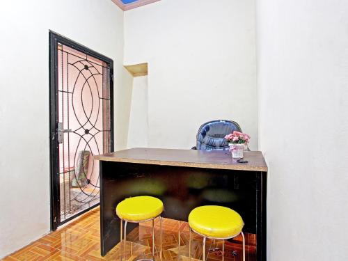 una mesa con dos sillas amarillas y una puerta en OYO 91818 Papaya Kos en Cilacap