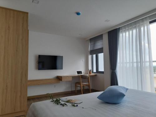 a bedroom with a bed with a television and a desk at Happy Home in Nha Trang