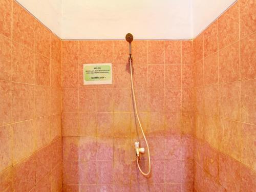 baño con ducha y un cartel en la pared en OYO 91818 Papaya Kos en Cilacap