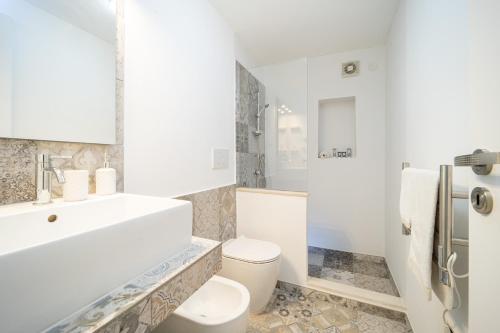 a white bathroom with a toilet and a sink at Tenuta del Barco WineRestaurant and Hospitality in Pulsano