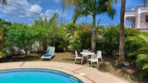 een patio met een tafel en stoelen naast een zwembad bij Tropical Palms apartment Mauritius in Pointe aux Cannoniers