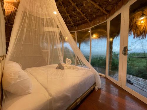 uma cama com uma rede mosquiteira num quarto com uma janela em Jantara Resort and Restaurant em Ban Bang O