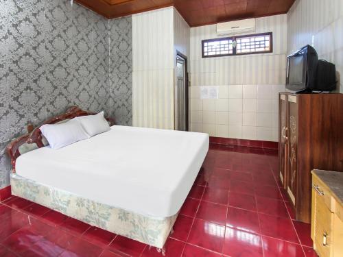 1 dormitorio con 1 cama blanca grande y TV en OYO 91829 Hotel Artha, en Tjakranegara