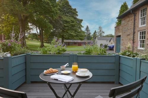 a table with bread and orange juice on a patio at Farlam Hall Hotel & Restaurant in Brampton