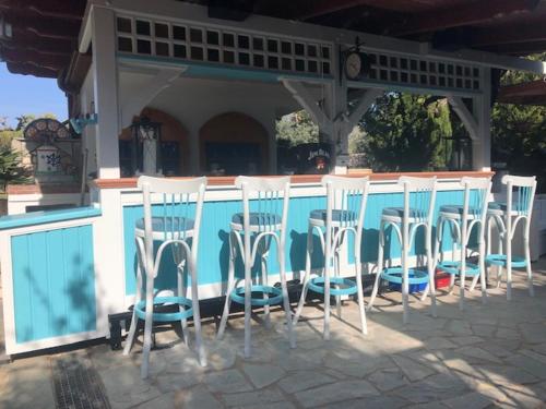 a group of white chairs sitting in front of a bar at Aegean Villas in Potos