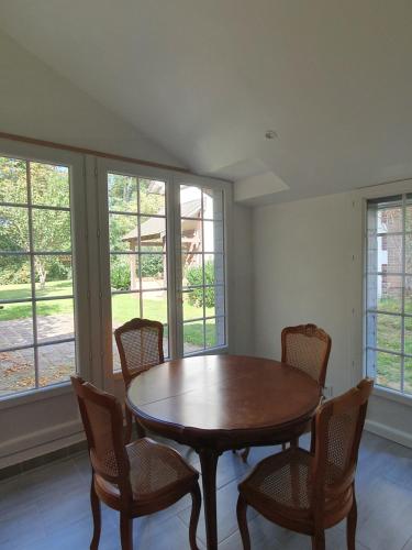 une salle à manger avec une table, des chaises et des fenêtres dans l'établissement Le Logis, à Coulonges-Ardennes