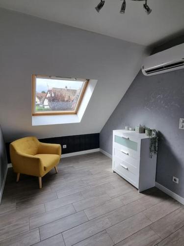 a room with a chair and a dresser and a window at Studio de la Demi Lune in Plobsheim