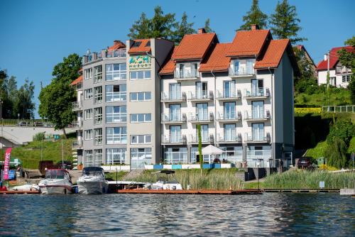 a building on the water with boats in front of it at Ach Mazury in Mikołajki
