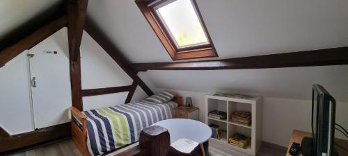a attic room with a bed and a window at La Berceuse Normande in Dampierre-sur-Avre
