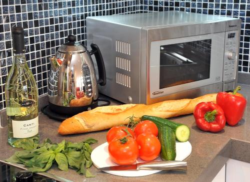 a counter with a microwave and some tomatoes and a loaf of bread at Highland Apartments by Mansley in Inverness