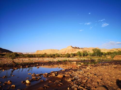 a river with rocks and mountains in the background at Dar Bilal in Aït Benhaddou