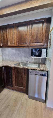 a kitchen with wooden cabinets and a sink and a microwave at APART-SKY A PIE DE PISTAS PARA 6PERSONAS - LA MOLINA ESTACIÓN in La Molina