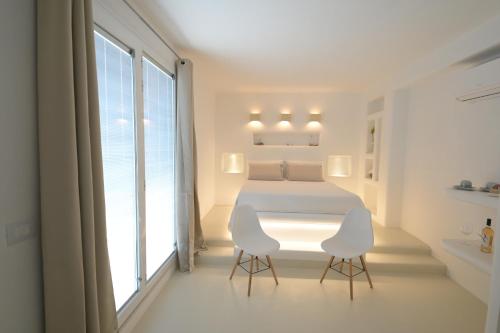 a white bedroom with a bed and two chairs at Tenuta del Barco WineRestaurant and Hospitality in Pulsano