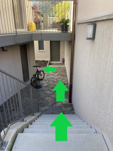 a stairway with green arrows pointing to a building at MarAvilia Apartment - vicino a Splash & SPA Tamaro in Monte Ceneri